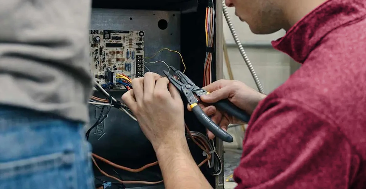 Technician working on electrical wiring inside an HVAC system
