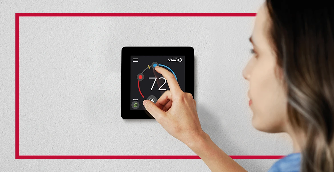 Person adjusting a Lennox smart thermostat on a wall.