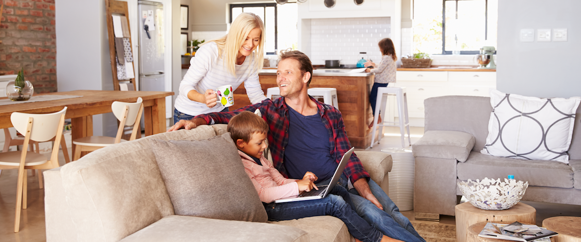 Mother, father, and son looking at laptop on couch